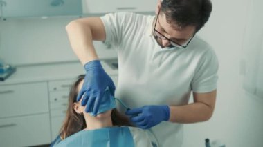 Diş hekimi sandalyesinde oturan hasta bir kızın yakın çekim görüntüsü. Diş hekimi dişleri tedavi eder.