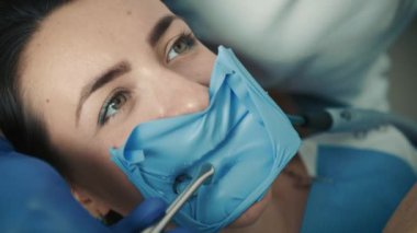 Diş hekimi sandalyesinde oturan hasta bir kızın yakın çekim görüntüsü. Diş hekimi dişleri tedavi eder.