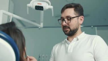 Olars 'taki beyaz dişçi, dişçi koltuğundaki hastayla iletişim kuruyor ve dişi doldurmadan önce mavi eldiven takıyor.