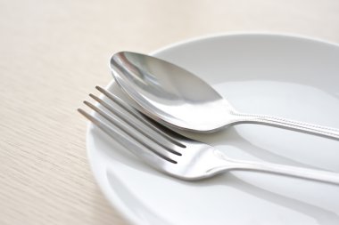 Ahşap bir masa üzerinde kaşık ve çatal ile plaka izole kapatın .