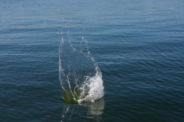 Su damlası, koyu mavi bir zeminde dalgalar ve dalgalanmalar yaratır..