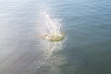 Su damlası, koyu mavi bir zeminde dalgalar ve dalgalanmalar yaratır..