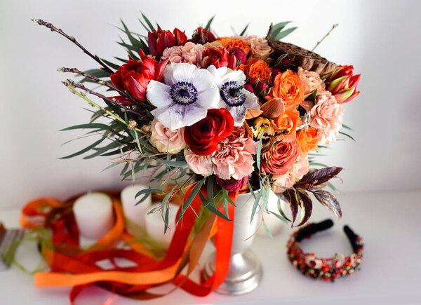 Large beautiful exotic wedding bouquet with orange ribbons in a vase.
