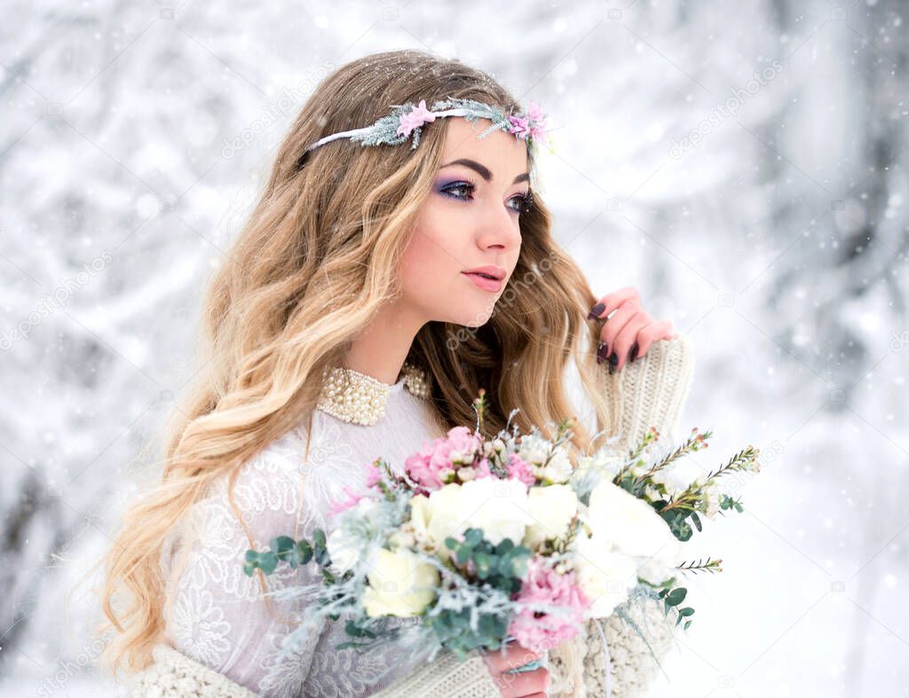 Beautiful winter bride with loose hair with a bouquet during a snowfall in the forest. The concept of beauty and winter wedding.
