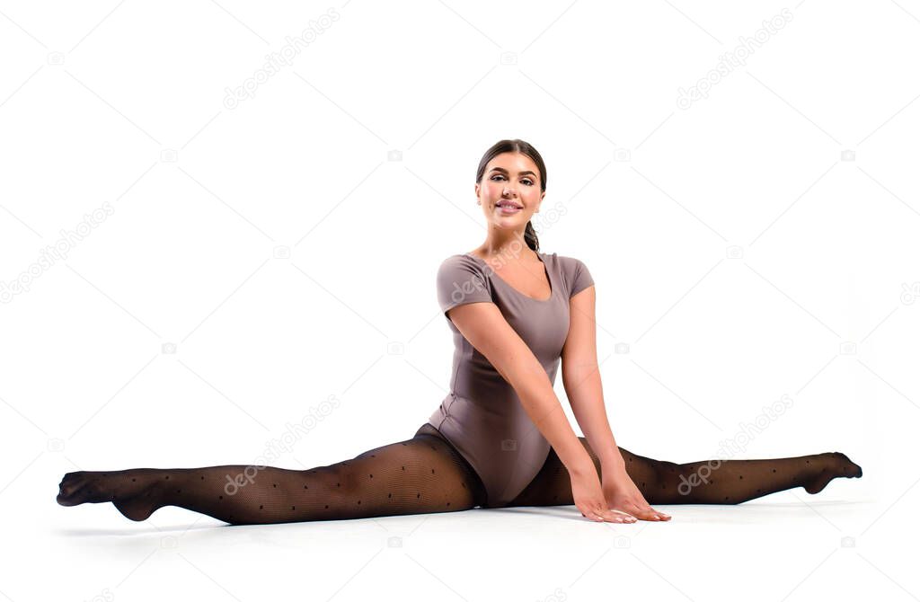 Smiling athletic girl in a bodysuit doing splits in a fitness Studio. Stretching exercise on a white background.