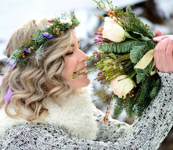 A beautiful woman with perfect smile holds a bouquet of roses and fir branches. Happy sincere winter outdoor portrait.