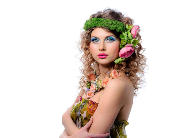 Beautiful young woman with flowers in curly hair and colorful makeup. Beauty portrait of a young beautiful model.