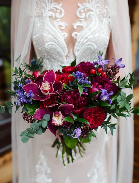 新娘手里拿着一束红花 穿着白花边的婚纱 — 图库照片