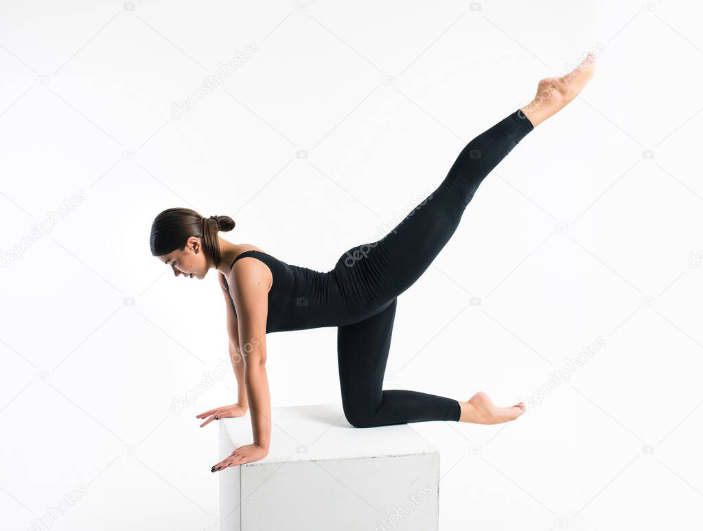Beautiful athletic woman gymnast in sportswear performs stretching fitness exercises on a white background. Sports motivation, physical education