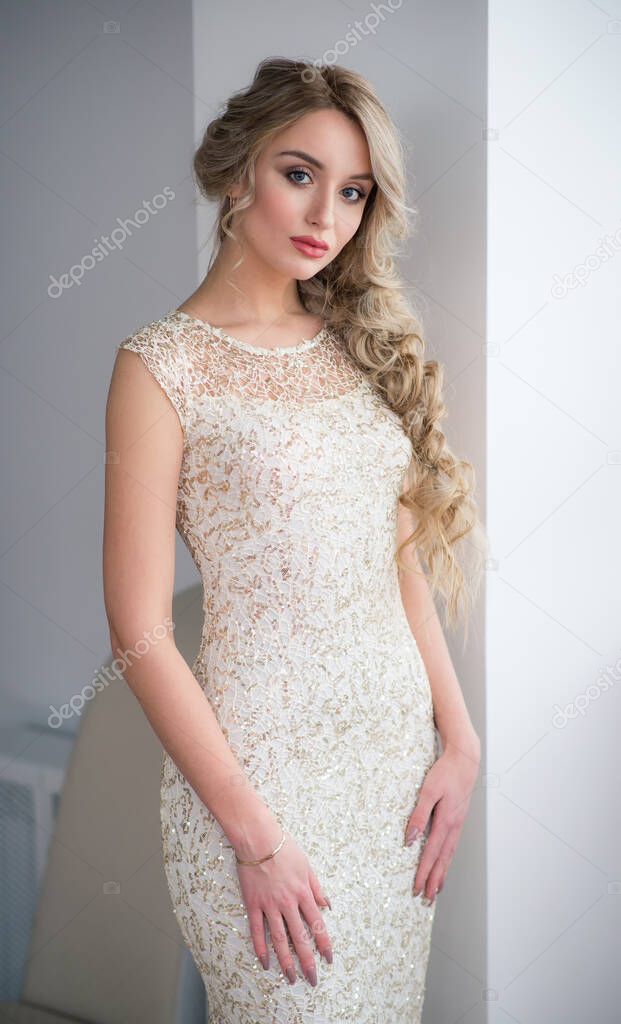 A young beautiful slender woman in a white evening dress. Beauty portrait of a model with a hairstyle