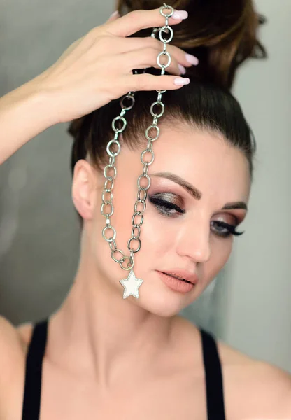 Attractive woman with a chain in her hands. Beauty portrait with jewelry