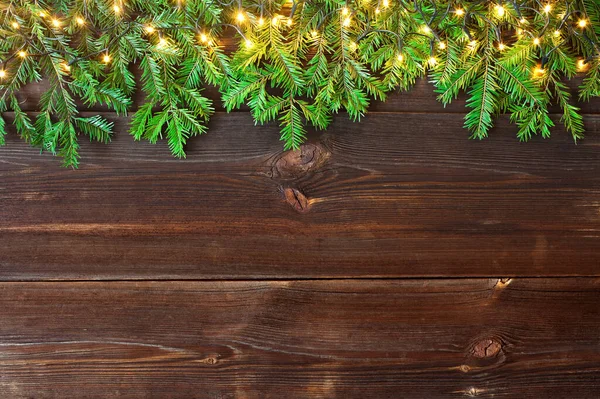 木製の素朴な板の上の公正な枝とクリスマスライト クリスマスの背景 高角度表示 — ストック写真