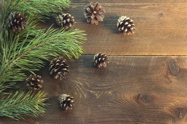 Pine grenar och kottar på trä bakgrund — Stockfoto