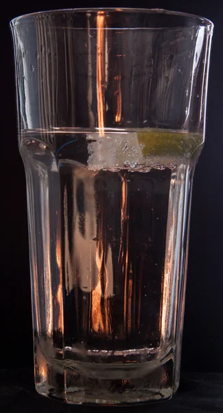 Pieza de cal caída en vidrio con agua en negro —  Fotos de Stock