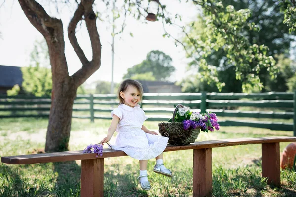 Menina Sentada Banco Aldeia Com Uma Cesta Lilases — Fotografia de Stock