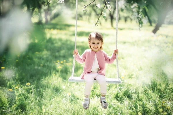 Ein Kleines Mädchen Schaukelt Auf Einer Schaukel Einem Blühenden Garten — Stockfoto