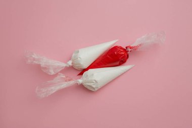 Buz torbalarında çok renkli camlar ve pembe masada yıldız şeklinde şekerlemeler. Tatlıları süslemek için ayarlandı. Zencefilli ekmek, browni ve pasta torbaları için krema. Pasta süsleme araçları.