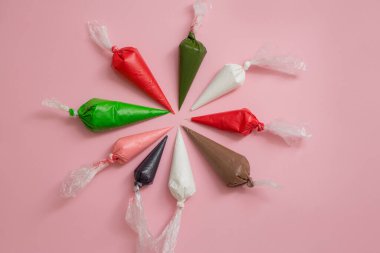 Buz torbalarında çok renkli camlar ve pembe masada yıldız şeklinde şekerlemeler. Tatlıları süslemek için ayarlandı. Zencefilli ekmek, browni ve pasta torbaları için krema. Pasta süsleme araçları.