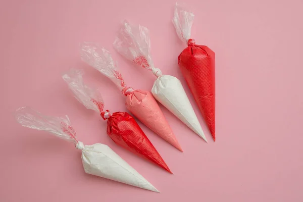 Buz torbalarında çok renkli camlar ve pembe masada yıldız şeklinde şekerlemeler. Tatlıları süslemek için ayarlandı. Zencefilli ekmek, browni ve pasta torbaları için krema. Pasta süsleme araçları.