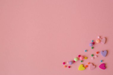 Metin için yer şablonu. Çok renkli kalpleri olan mutlu sevgililer günü pembe kartı. Mücevher ve bijouterie yaratmak için çok renkli boncuklar.