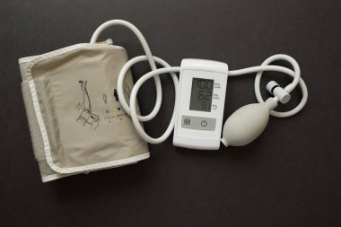 Siyah arka planda tıbbi elektronik tonometre. Bir hastaya kan basıncını ölçen Sphygmomanometre veya tonometre.