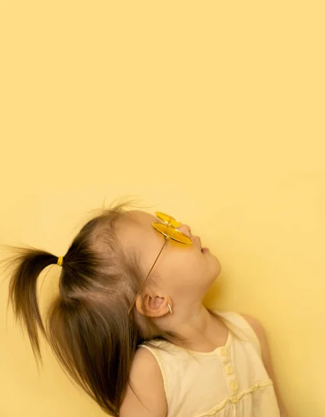 Una Niña Con Gafas Sol Sobre Fondo Amarillo Mira Hacia —  Fotos de Stock