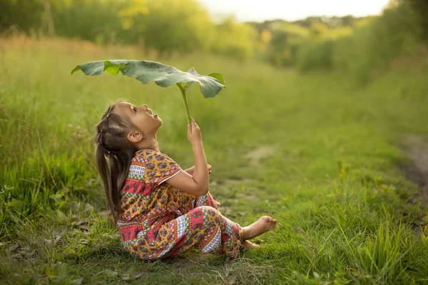 Ein Kleines Mädchen Sitzt Auf Dem Rasen Geschützt Vor Dem — Stockfoto