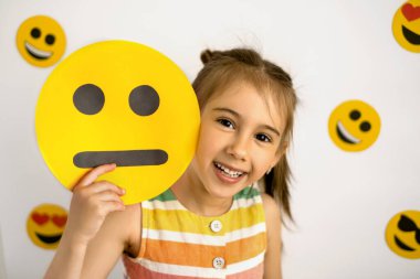 Mutlu, neşeli bir kız mutsuz, karton bir gülümsemenin arkasından dışarı bakar. Ne olursa olsun pozitif ol. Sanguine insanı. Temperament: kolerik, melankolik, sanguin, balgamlı. Dünya emoji günü