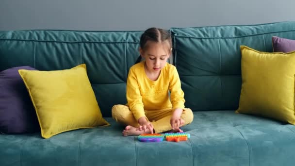 Uma Menina Está Brincando Quarto Sofá Verde Com Brinquedo Popit — Vídeo de Stock