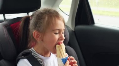 Beş yaşında bir kız, araba koltuğunda emniyet kemeri takıyor ve sosisli Fransız çöreği yiyor. Yolculuk sırasında arabada bir şeyler atıştır. Uzun bir yol. Aç bir çocuk. Aile gezisi arabayla. Fast food