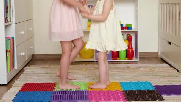 赤脚姐姐们在儿童房里玩着用五颜六色的拼图做成的矫形外科结构模块化按摩床 防止脚踏平的玩具 — 图库视频影像