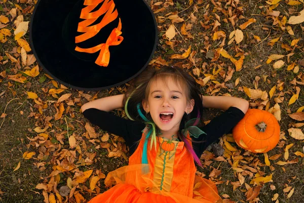 Een Meisje Een Heksenkostuum Ligt Herfstbladeren Naast Een Pompoen Een — Stockfoto