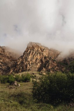 Bulutlar ve sisle kaplanmış muhteşem dik dağlar.