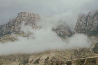 Bulutlar ve sisle kaplanmış muhteşem dik dağlar.