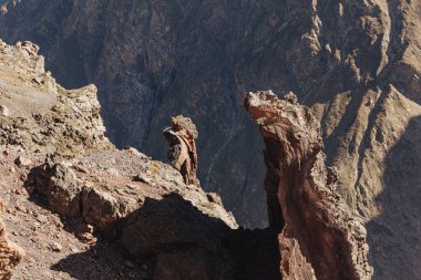 Parlak güneşin aydınlattığı keskin kahverengi kayalar.