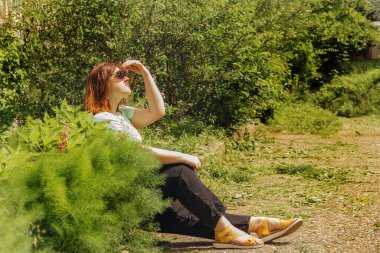 Açık yeşil bluzlu kızıl kız ve yeşil kotlu siyah kız.