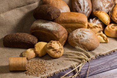 Ekmek, kulak ve tahıl taneleri ahşap masada.