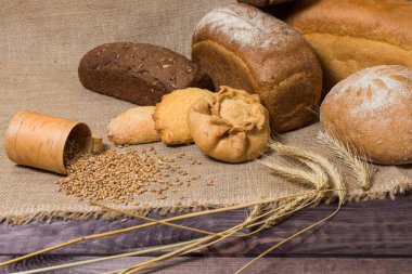 Tahta masanın üzerinde ekmek, kulak ve tahıl taneleri var. Kırsal biçim