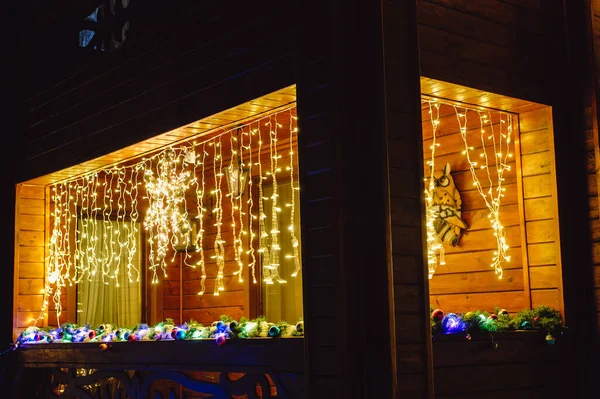 Beautiful Christmas decorations outside the house at night. House decorated with glowing lights for Christmas.