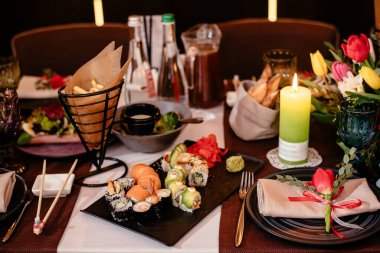 Şölen masasındaki bir restoranda suşi. Tabaklar, çatal bıçaklar ve abur cuburlarla dolu şenlik masası. Zarif bir sofra..