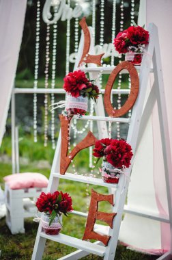 Dekoratif mektuplar aşk ve kırmızı şakayık çiçekleri tahta bir vazoda cam bir vazoda. Düğün ve Sevgililer Günü için fotoğraf alanı. Güzel, şık, açık hava fotoğraf bölgesi..