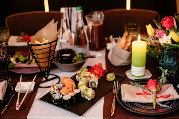 Şölen masasındaki bir restoranda suşi. Tabaklar, çatal bıçaklar ve abur cuburlarla dolu şenlik masası. Zarif bir sofra..