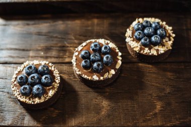 Koyu ahşap arka planda yaban mersinli çikolatalı turtalar. Tatil masası için güzel porsiyon kekler. Taze yaban mersinli tatlı.