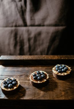 Koyu ahşap arka planda yaban mersinli çikolatalı turtalar. Tatil masası için güzel porsiyon kekler. Taze yaban mersinli tatlı. Metin için yer