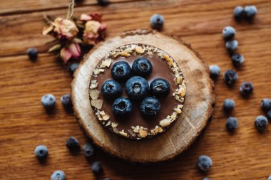 Tahta arka planda taze yaban mersinli ve çikolatalı lezzetli tart. Moda bir tatlı. Üst görünüm