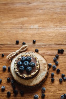 Tahta arka planda taze yaban mersinli ve çikolatalı lezzetli tart. Moda bir tatlı. Mesaj için yer. kopyalanmış boşluk