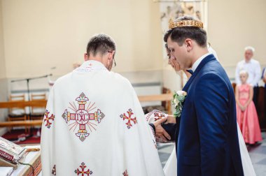 Gelin ve smokinli damat beyaz gelinlik giyip tapınaktaki düğün töreninde dikiliyor..