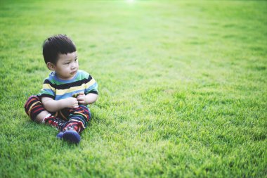 Portre çocuk oturur ve bahçede düşünür. Düşünme Alanı Olan Küçük Çocuk Portresi.