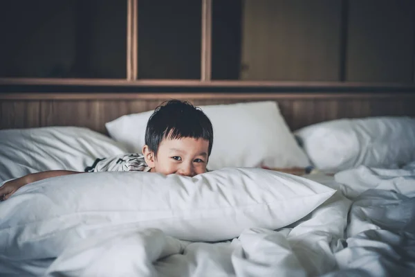 줄무늬 티셔츠를 소년이 긴장을 침대에 따뜻하고 잠자리 분위기를 만끽하고 스러운 — 스톡 사진
