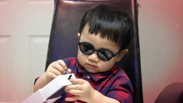 선글라스를 꼬마는 박스에 것들에 합니다 선글라스를 의자에 아이의 — 스톡 사진